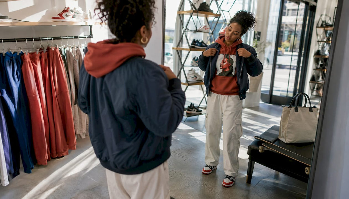 Young woman trying streetwear jacket in boutique
