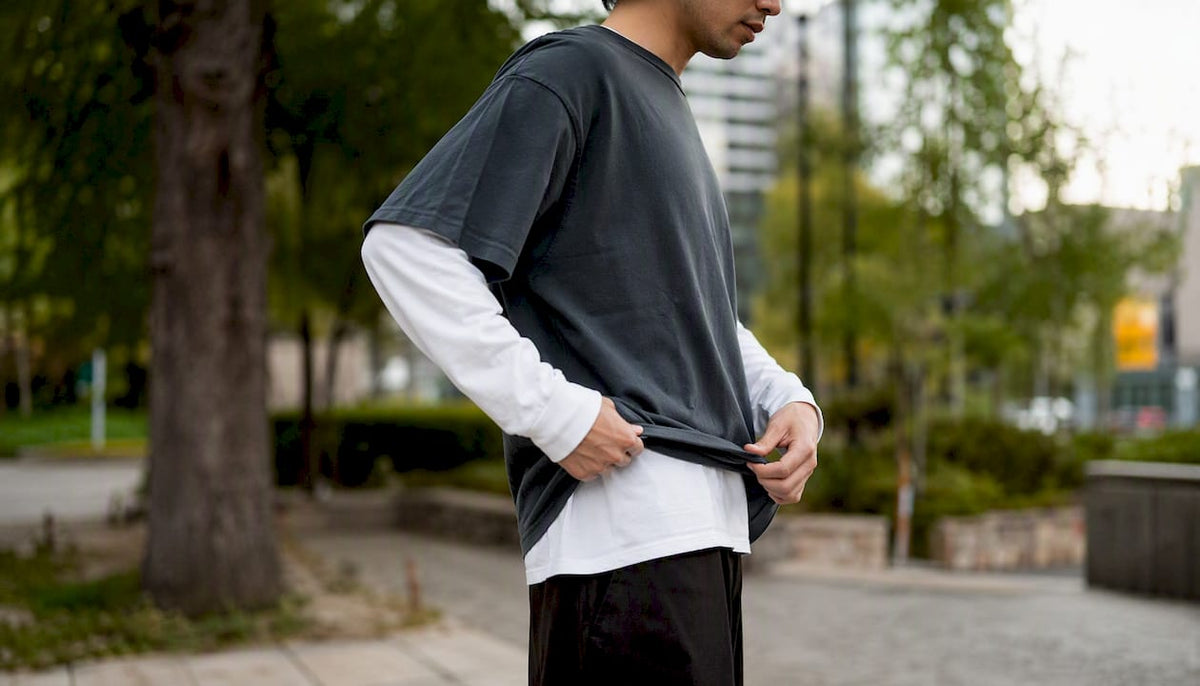 Person layering t-shirts in urban alley