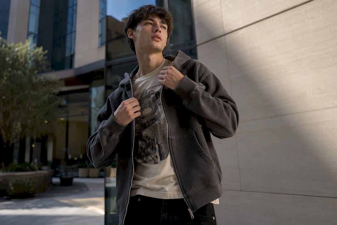 Person adjusting zip hoodie on urban plaza